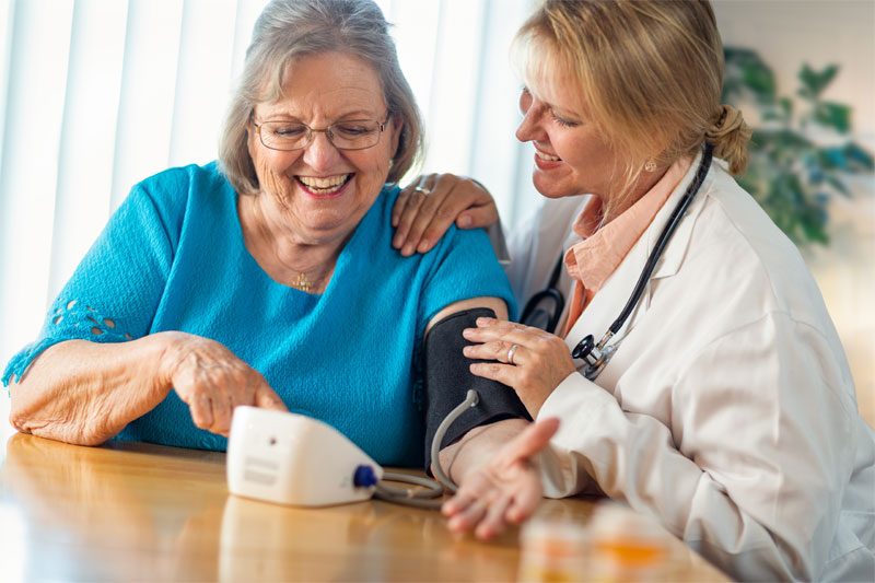 a caregiver measuring blood pressure of her patient in an in-home personalized care environment